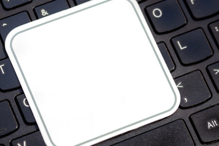 Simple blank white square label on a laptop computer keyboard, empty sticker template for logo design, close-up detail, modern business tech startup branding logo copy space concept, nobody, angleの写真素材