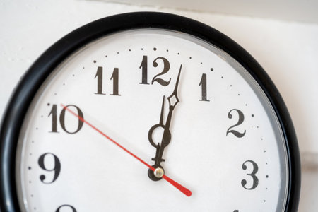Simple clock close-up, showing minutes past noon just past 12 AM or twelve PM time concept....