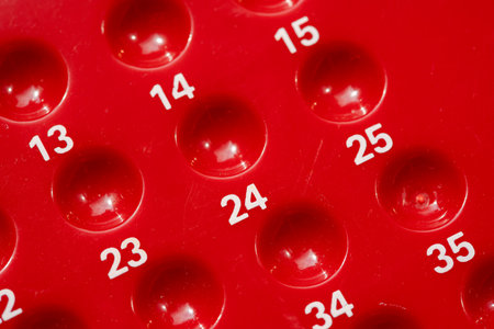 Red numbered bingo game board close-up detail, empty slots holes for bingo or lottery, random number sequence concept, row, game of chance and game theory maths abstract concept symbol, nobodyの写真素材
