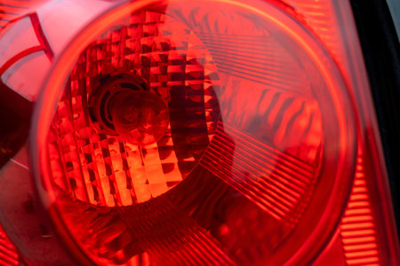 Extreme close-up of red car taillight reflector texture, bulb detail, automobile rear back stop light lights design, vehicle safety equipment, brake signal component, abstract red light patternの写真素材