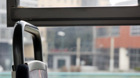 Closeup of a public transport seat handle in an older bus or tram with blurred city buildings...