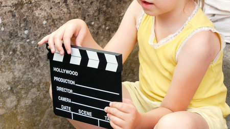 Young anonymous girl holding a clapperboard for movie production, child playing with film slate outdoors cinematic playtime concept with director board filmmaking game play creative activityの写真素材