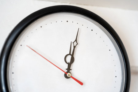 Minimal wall clock without numbers, analog dial with black hands red second hand on empty blank white face with dot markers closeup time management flow planning schedule countdown punctuality conceptの写真素材