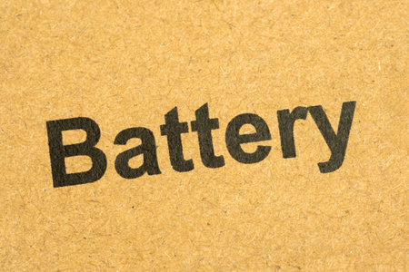 Closeup of black printed word battery on a brown cardboard box surface, macro detail view of...