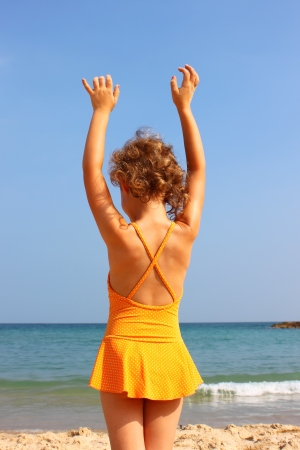 child on the beach, holding her hands upの写真素材