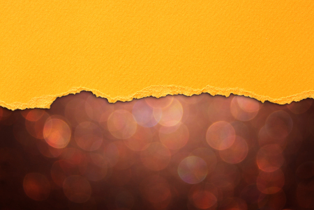 brown bokeh lights and orange torn paperの写真素材
