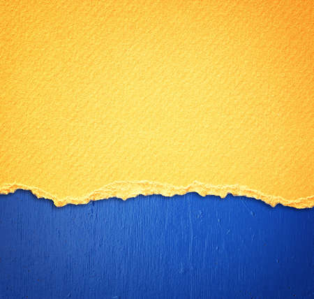 yellow textured torn paper over blue wall backgroundの写真素材