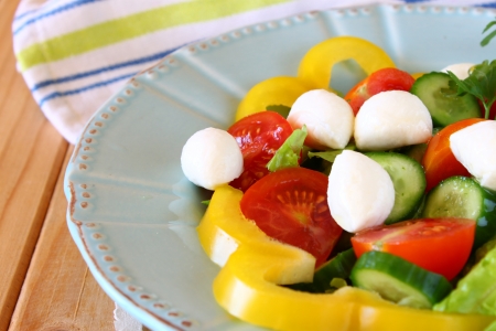 salad with mozzarella and fresh vegetables on wooden table backgroundの写真素材