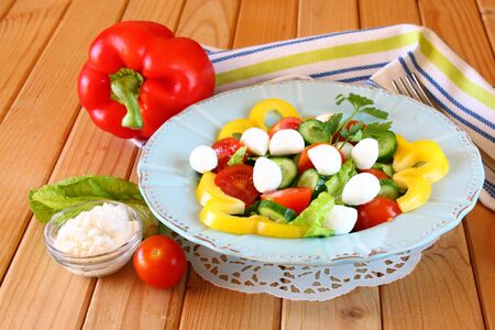 salad with mozzarella and fresh vegetables on wooden table background の写真素材