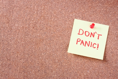 cork board with pinned yellow note and the phrase  dont panic  written on it  room for text の写真素材