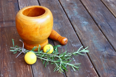 fresh rosemary herbs in wooden pestle and mortar on wooden tableの写真素材