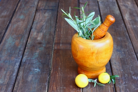 fresh rosemary herbs in wooden pestle and mortar on wooden tableの写真素材