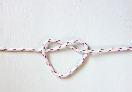 Heart Shaped Knot on a rope on blue wooden textured backgroundの写真素材