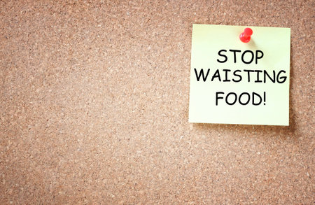 sticky note over cork board with the phrase stop waisting food  room for text   の写真素材