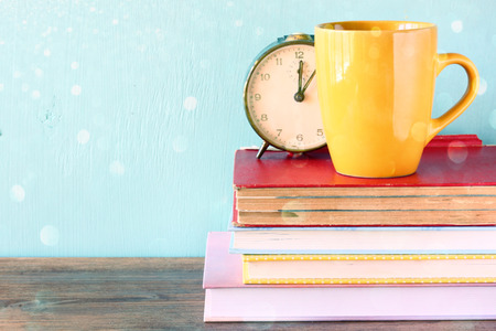 vintage clock and yellow mag over stack of books   の写真素材