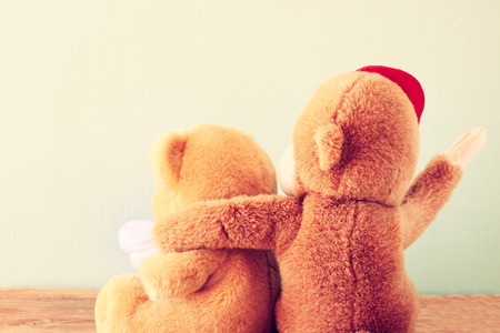 two teddy bears on a shelf with arms around each other  retro vintage filter  の写真素材