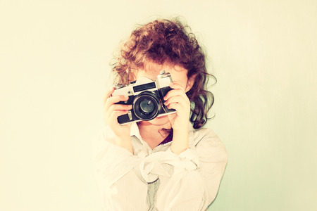 Cheerful kid holding old camera  retro filter room for text   