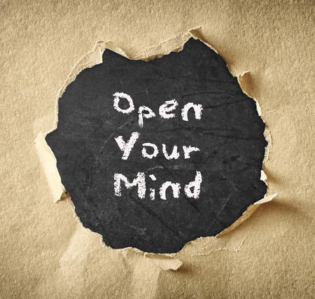 the phrase open your mind written over chalkboard through torn paper  の写真素材