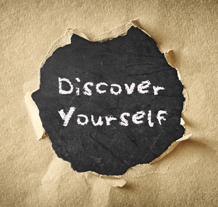 the phrase discover yourself written over chalkboard through torn paper  の写真素材