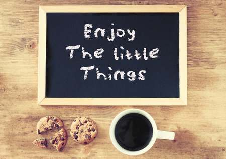 top view of coffee cup cookies and blackboard with the phrase enjoy the little things written on it   の写真素材