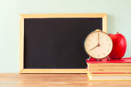 empty blackboard , apple, clock and stack of books   の写真素材