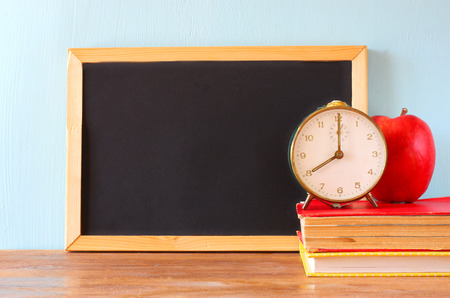 empty blackboard , apple, clock and stack of books   の写真素材