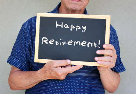 Close up of senior man holding blackboard with the phrase happy retirement written on it  の写真素材