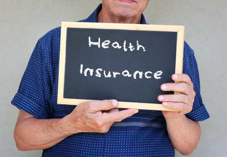 close up of senior man holding blackboard with the phrase health insurance written on it   の写真素材