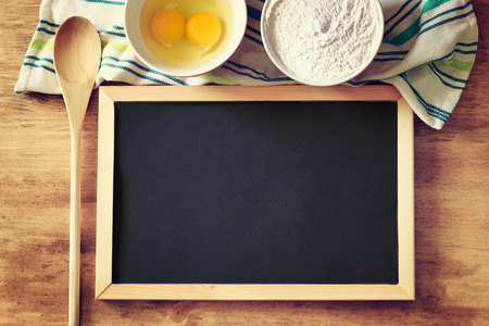 top view of blackboard and wooden spoon over wooden table  filtered image  の写真素材