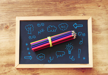 top view of pencils stack over blackboard and various drawingの写真素材