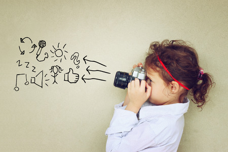 Concept of cute kid looking through vintage cameraの写真素材
