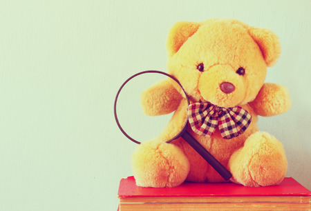 cute teddy bear sitting over stack of booksの写真素材