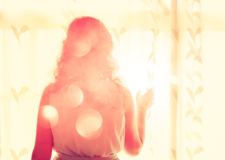 young woman near window waiting for someoneの写真素材