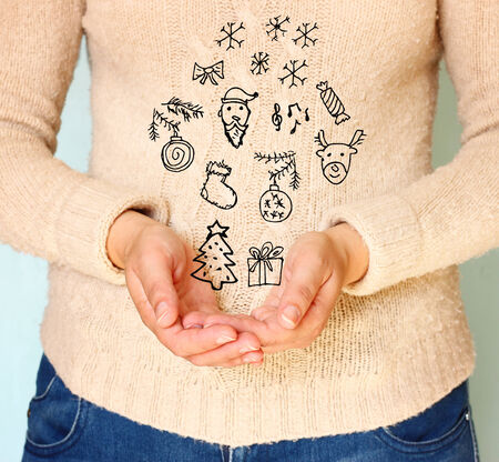 young woman hands in cupped shape showing various christmas icons  の写真素材