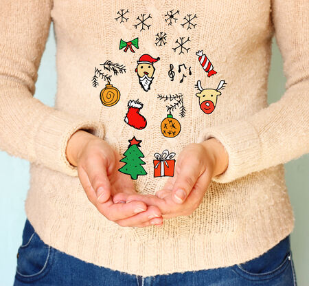 young woman hands in cupped shape showing various colorful christmas icons  の写真素材
