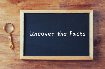Top view of blackboard with the phrase uncover the facts written