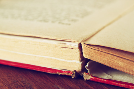 Open old book over wooden table. macro image with selective focuse. filterted imageの写真素材