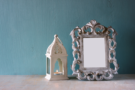 low key image of vintage antique classical frame and Lantern    on wooden table. filtered imageの写真素材