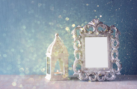 low key image of vintage antique classical frame and Burning candle on wooden table and glitter lights background . filtered imageの写真素材
