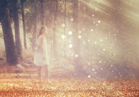 surreal blurred background of young woman stands in forest. abstract and dreamy concept. image is textured and retro tonedの写真素材