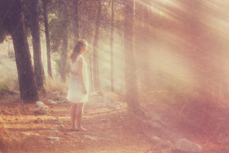 surreal blurred background of young woman stands in forest. abstract and dreamy concept. image is textured and retro tonedの写真素材