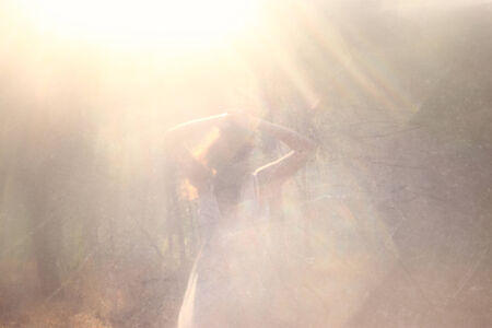 surreal blurred background of young woman stands in forest. abstract and dreamy concept. image is textured and retro tonedの写真素材