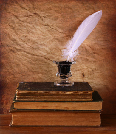 low key image of white Feather, inkwell and ancient books on old wooden tableの写真素材