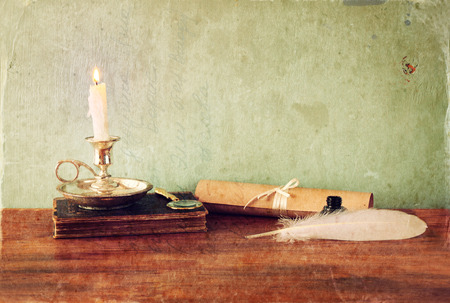 low key image of white Feather, inkwell and candle on old wooden table. image texturedの写真素材