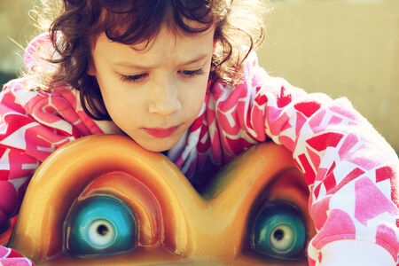 cute little girl playing and having fun on the playground, in an autumn day. retro filtered imageの写真素材