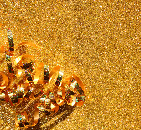 top view image of curly golden ribbon over textured glitter backgroundの写真素材