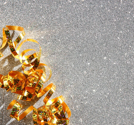 top view image of curly golden ribbon over textured silver shiny backgroundの写真素材