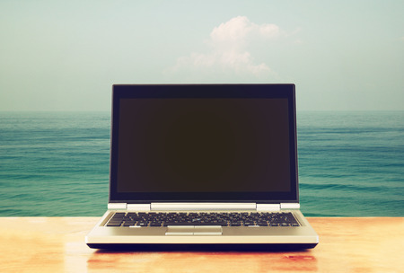 laptop with blank screen over wooden table outdoors and tress