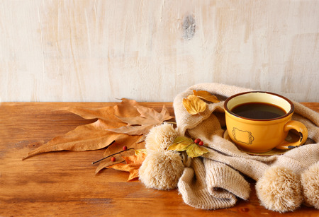 Cup of black coffee with autumn leaves, a warm scarf on wooden background. filreted imageの写真素材