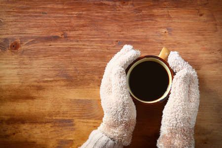 Top view of Female hands with a hot coffee, on wooden backgroundの写真素材